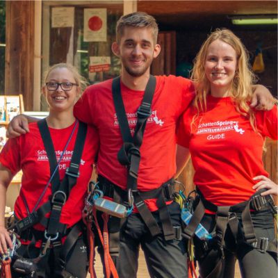 Ein Mitarbeiter und zwei Mitarbeiterinnen stehen in voller Ausrstung Arm in Arm