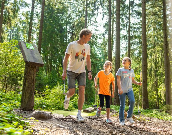 Erwachsener und zwei Kinder gehen zum Adventure Golf 