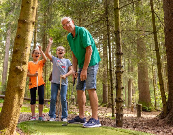 Besucher spielt mit 2 Kindern Adventure Golf
