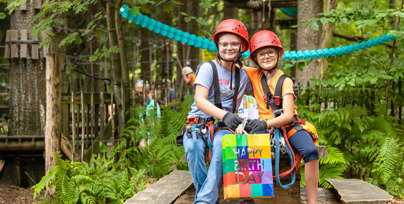Zwei befreundete Kinder sitzen in einer Umarmung vor dem Kletterpark