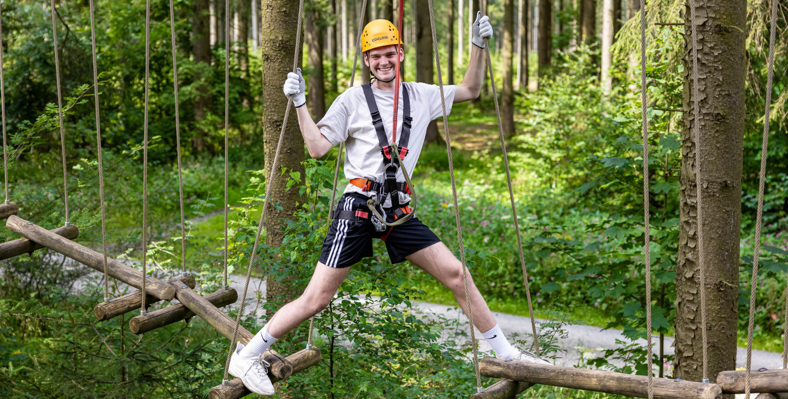 Junger Mann in einer balanciert in einem Kletterelement