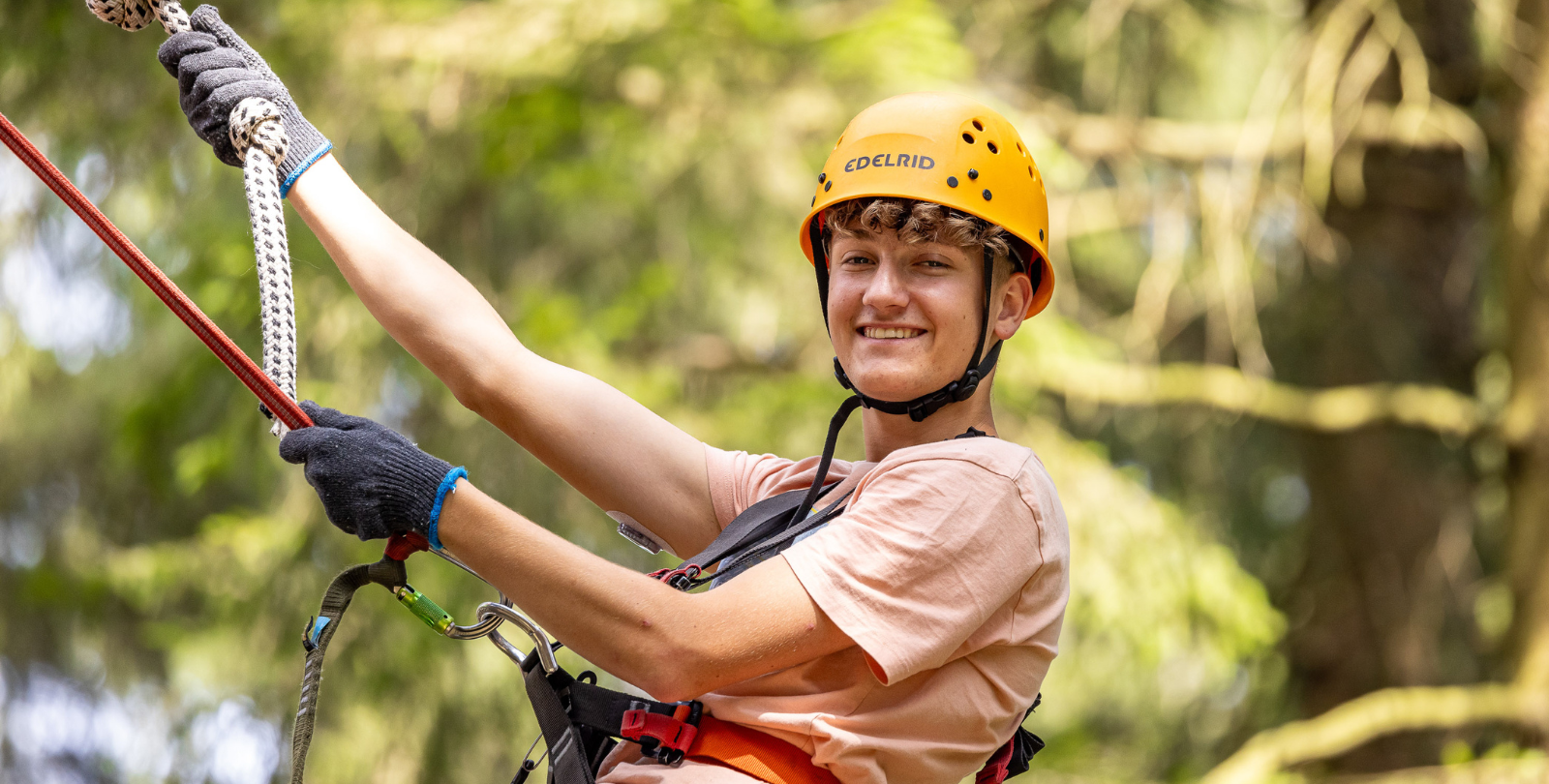 Jugendlicher im Halbportrt in Klettersituation schaut in die Kamera