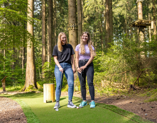 Zwei junge Frauen stehen auf einem Golfparcour